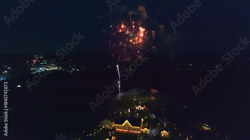 Colorful green fireworks light up the night sky, creating a magical atmosphere over the city. The view showcases a festive scene with buildings illuminated below, enhancing the celebration.