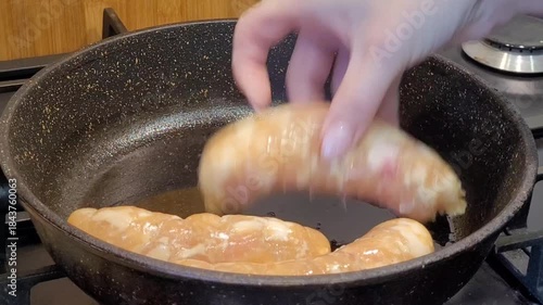 The process of putting sausages in a pan. Cooking sausages.