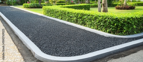 Black Gravel Path with Concrete Border and Green Hedges in a Lush Garden