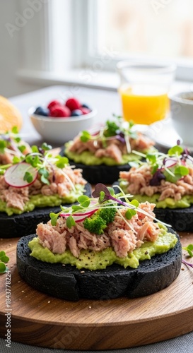 Gourmet breakfast with black charcoal bread, avocado, and fresh radish topped with tuna