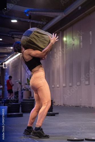 A woman is carrying a large bag on her back while in a gym setting