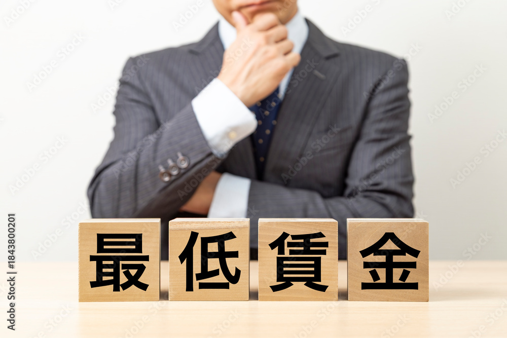 Obraz premium 「最低賃金」と書かれたブロックとビジネスマン