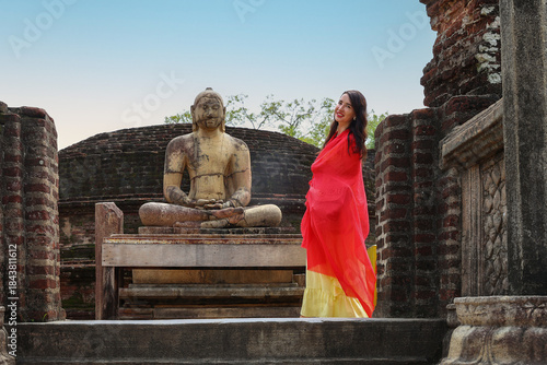 Woman in Sari Poses with Ancient Buddha Statue at Historic Temple Ruins