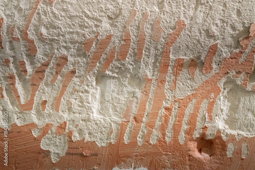 Rough texture of a wall with peeling plaster and traces of removed paint, abstract background with a natural chaos of lines and textures.