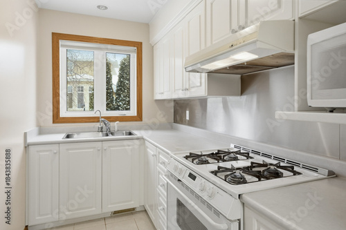 Kitchen with a white stove and oven, a sink, and a window