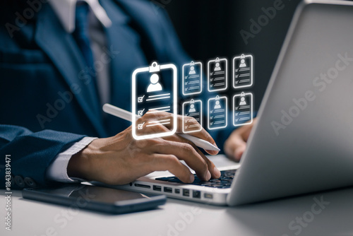 A recruiter reviews multiple digital resumes on a laptop, representing candidate databases, talent screening, recruitment technology, employee evaluation, and modern hiring systems.