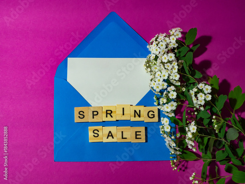 Spring sale! Blue envelope with a white sheet of paper for a message, a spiraea branch, on a pink background. Spring women's discount concept.