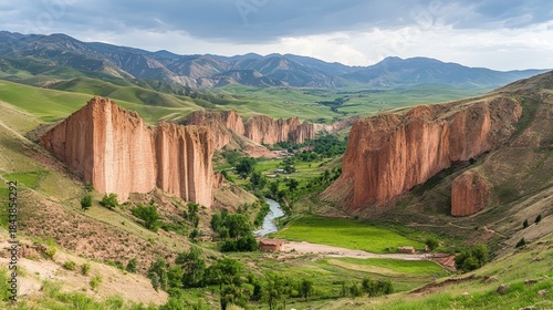 Majestic Red Rock Cliffs Guard Verdant Valley with Winding River and Distant Mountains