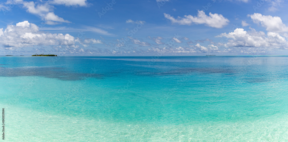Fototapeta premium Relaxing blue ocean view beneath bright sunny sky with soft white clouds, idyllic tropical Mediterranean seascape, calm summer travel nature scene, peaceful coastal pattern background inspiration