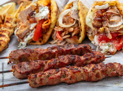 Fototapeta Naklejka Na Ścianę i Meble -  Gyro sliced meat pita bread wraps, pork souvlaki skewers, traditional street food, closeup