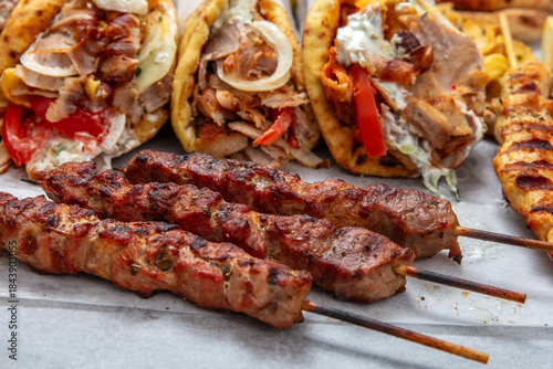 Fototapeta Naklejka Na Ścianę i Meble -  Gyro sliced meat pita bread wraps, pork souvlaki skewers, traditional street food, closeup