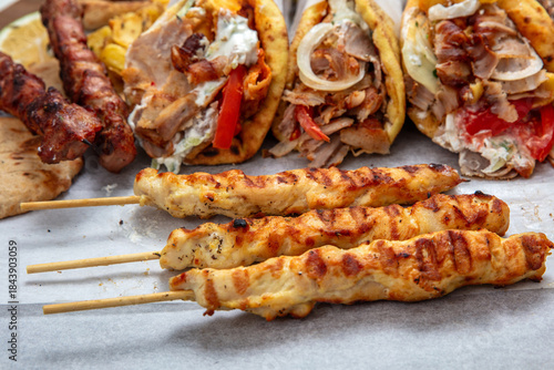 Fototapeta Naklejka Na Ścianę i Meble -  Gyro sliced meat pita bread wraps, chicken souvlaki skewers, traditional street food, closeup