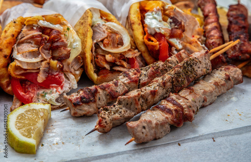 Fototapeta Naklejka Na Ścianę i Meble -  Gyro sliced meat pita bread wraps, pork souvlaki skewers, traditional street food, closeup