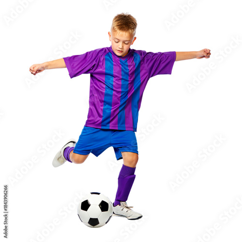 A young boy athlete in uniform kicking a soccer ball during an active game