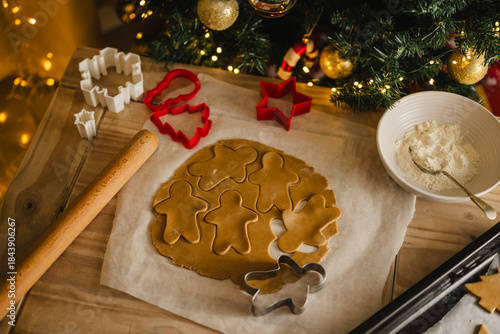 Holiday background. Uncooked raw Christmas gingerbread cookies with cookie cutters on a table, top view, flat lay