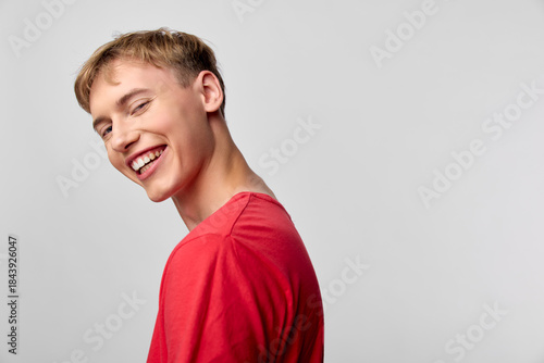 Принти на полотні Smiling male in a red shirt, turned slightly away from the camera, exuding casua