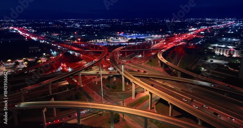Beautiful night cityscape with stunning illumination. Drone flight around lively intersection with fast moving cars.