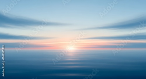 A tranquil ocean scene at sunrise with blurred clouds reflecting on the calm water