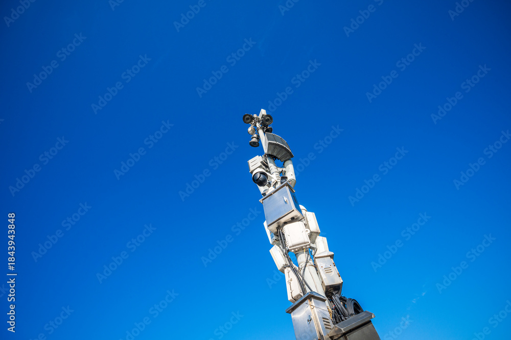 Obraz premium Towering Surveillance: A Look at Modern Security Systems Against a Bright Blue Sky