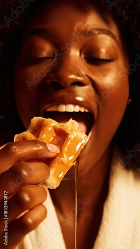 Young woman enjoys waffles with syrup in a cozy setting at home during breakfast time