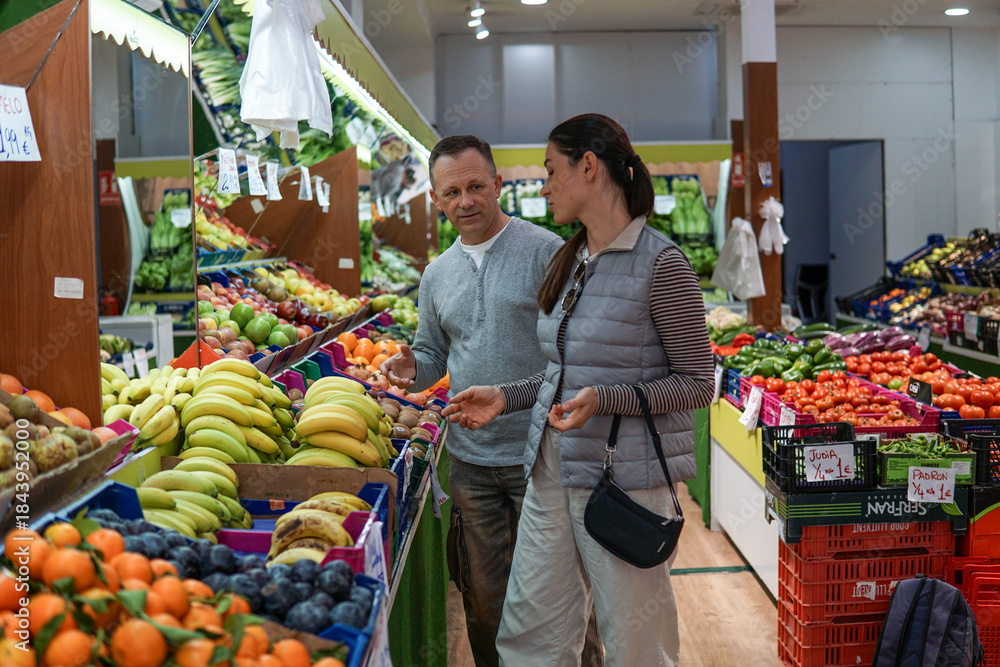 Obraz premium middle-aged man and woman buying fruits and vegetables at an outdoor market