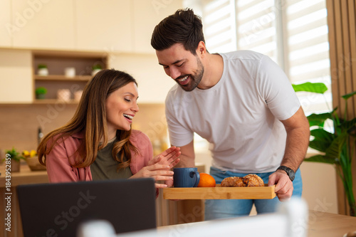 Partner bringing surprise breakfast to smiling beloved woman