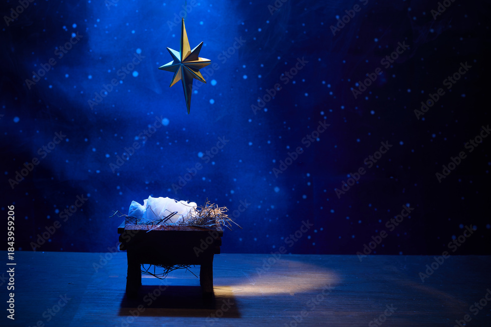 Obraz premium Starry Night Nativity. A nativity scene under a glowing star in a deep blue, starry background