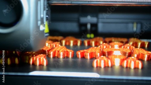 3D printer close up. Working 3D printer in process of printing object from molten orange plastic. 3D printer creating model by flowing liquid plastic from extruder of printer. 3D printing technology