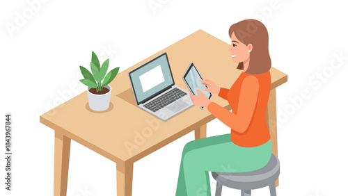 Woman working on laptop and tablet at home office desk