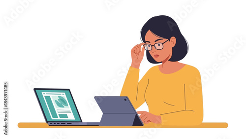 Woman working on laptop and tablet in yellow sweater