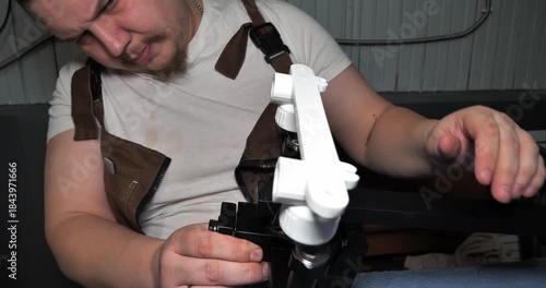 A professional plumber connects white plastic pipes to a black shower faucet bracket. The plumber carefully assembles the components of a bathroom plumbing system before installation in the workshop.