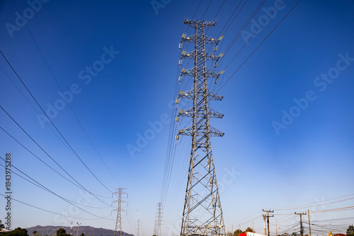High Voltage Transmission Tower on Sunny Day with blue sky and mountain