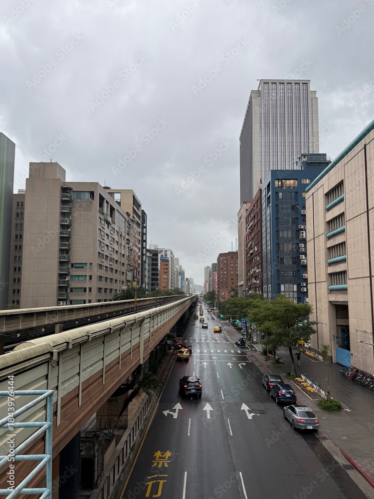 Obraz premium Taiwan City Street: View of a busy city street in Taiwan flanked by tall skyscrapers and modern architecture under a bright sky.