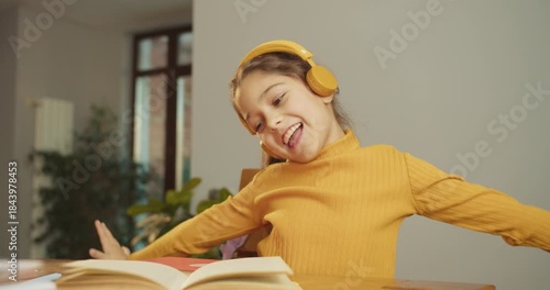 smiling white girl singing along with headphones at table