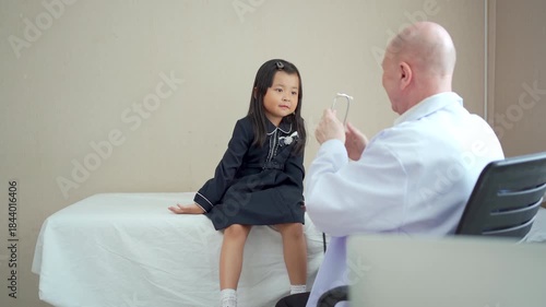 Pediatrician examining young girl with stethoscope in clinic.