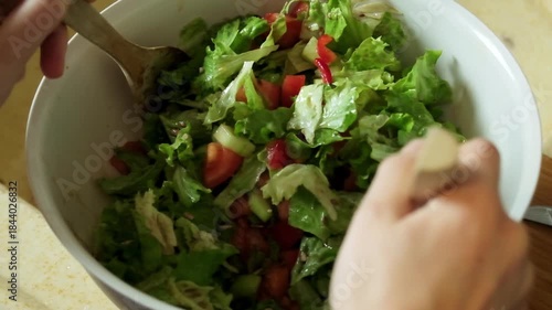 Slow motion video of a fresh salad being gently mixed and tossed using a wooden spoon

