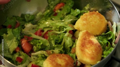 Slow motion video of crispy nuggets being placed on top of a fresh salad for added protein

