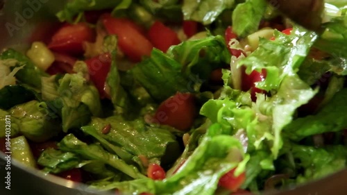 Slow motion video of a fresh salad being gently mixed and tossed using a wooden spoon

