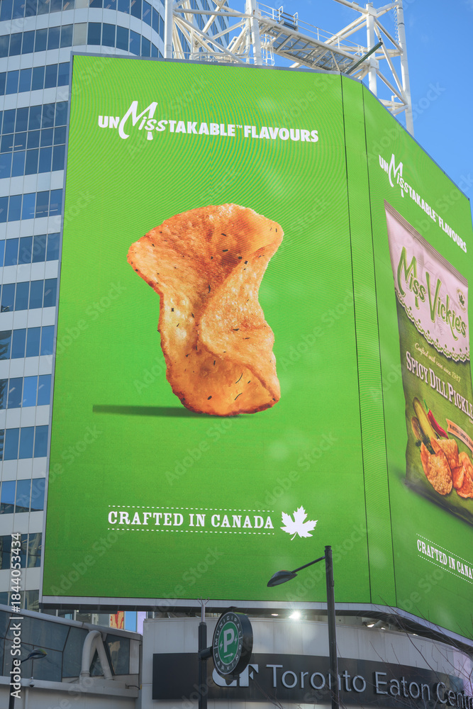 Fototapeta premium electronic sign featuring advertisement for Miss Vickie’s Spicy Dill Pickle, a Canadian kettle-cooked potato chip brand (PepsiCo) near Sankofa Square, Toronto