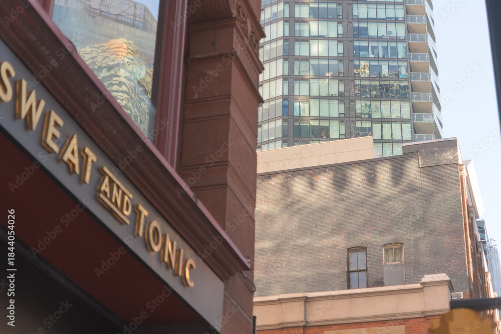 Naklejka premium defocused sign of Sweat and Tonic, a fitness center, located at 225 Yonge St, The Ryrie Building, Toronto (contrast of architecture styles)
