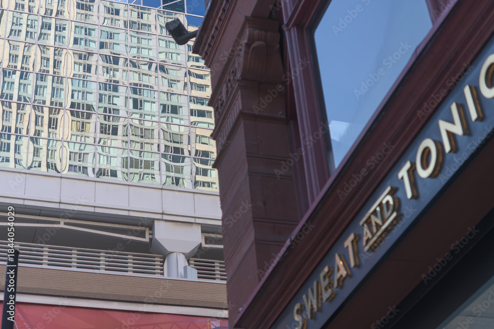 Naklejka premium defocused sign of Sweat and Tonic, a fitness center, located at 225 Yonge St, The Ryrie Building, Toronto (contrast of architecture styles)