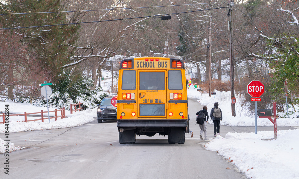 Naklejka premium yellow school bus stopping on residential street after snow