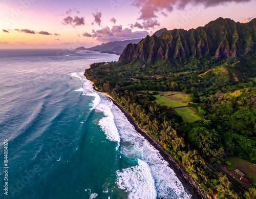 Aerial view captures coastal beauty with dramatic cliffs, ocean waves, and vibrant sunset