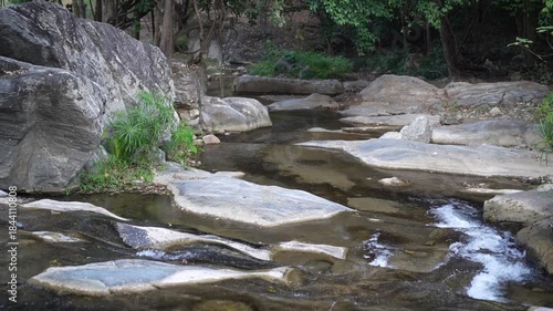 waterfall stream with rocks stones on nature clear flow slow motion water from trees in jungle rainforest or natural forest at Phalad waterfall in Lan sang national park Thailand for summer landscape