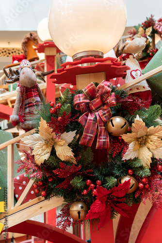 Lively holiday display featuring a bright lantern set among a lush Christmas wreath with red ribbons, gold ornaments, and pine accents. Perfect for festive home decor and seasonal celebrations.