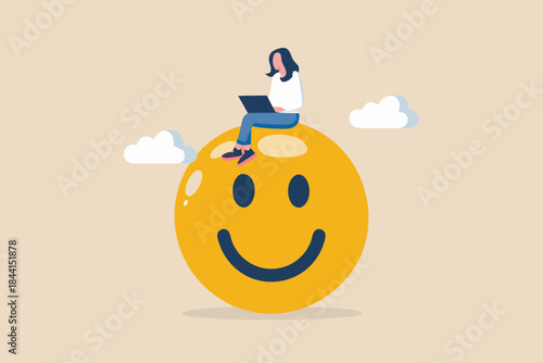 A woman working on a laptop atop a large cheerful yellow smiley face