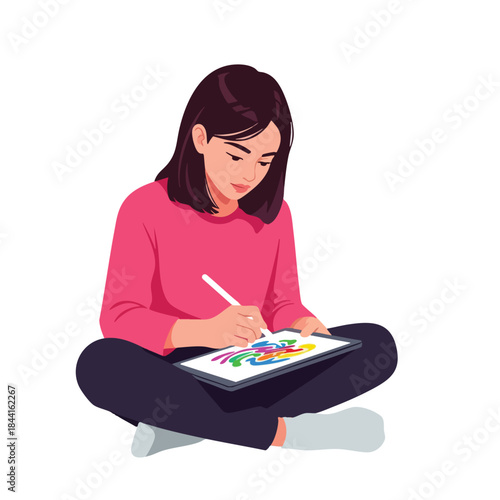 A woman in pink draws on a tablet with a stylus while cross-legged