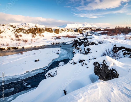 Snowy river winding through a winter landscape, mountains in the distance under a bright blue sky