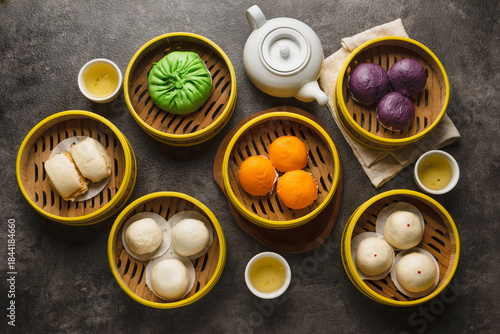 Foto Assortment of colorful dim sum in bamboo steamers with tea.