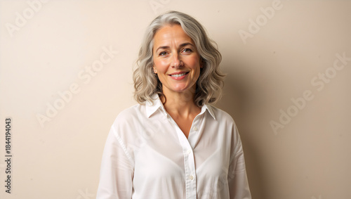 Portrait of a confident mature woman with grey hair. Happy middle aged female smiling at camera. Natural skincare and aging concept